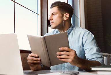 Photo of Man listening to audiobook at table in cafe