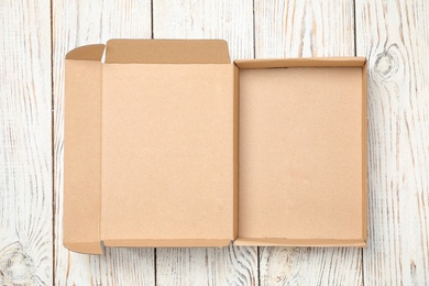 Photo of Open cardboard box on white wooden background, top view