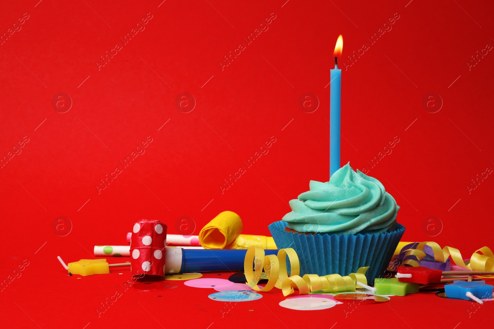 Photo of Delicious birthday cupcake with turquoise cream and burning candle on red background. Space for text