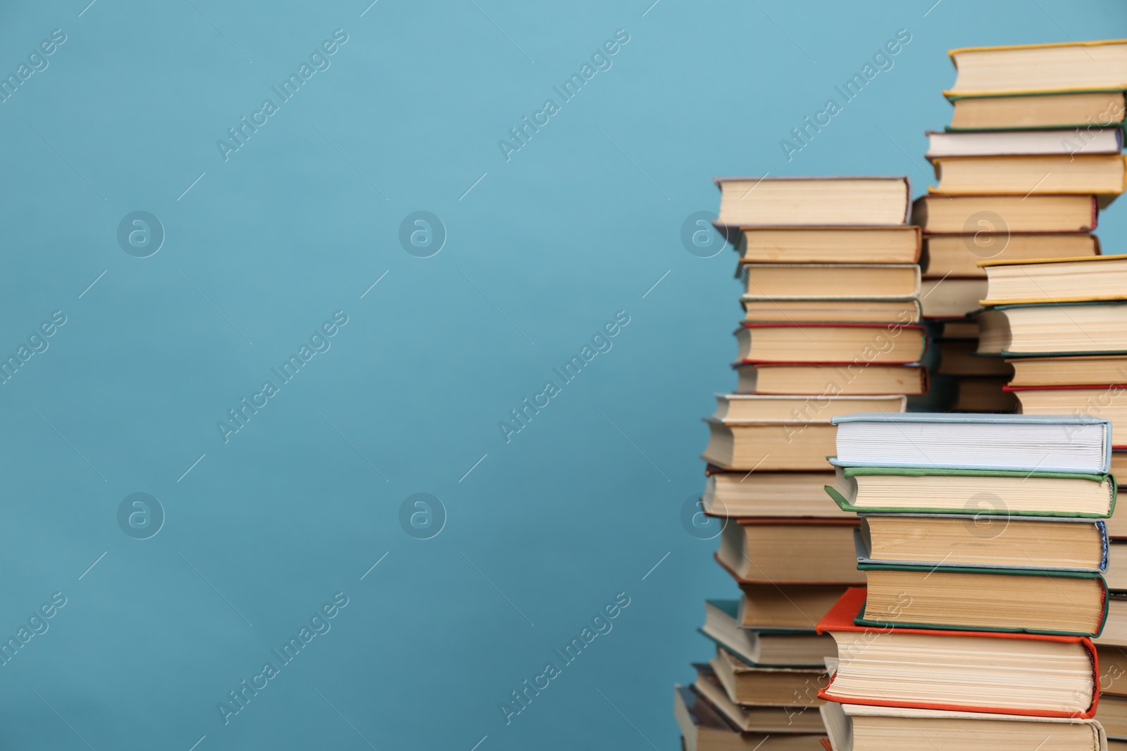 Photo of Many hardcover books on turquoise background, space for text. Library material