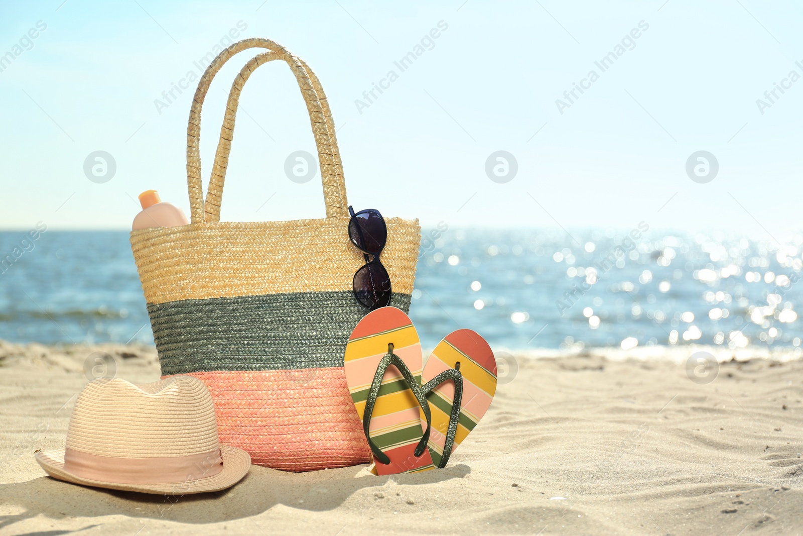 Photo of Bag and beach objects on sand near sea, space for text