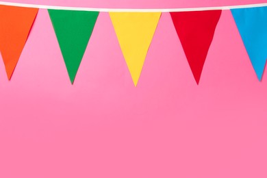 Bunting with colorful triangular flags on pink background. Space for text