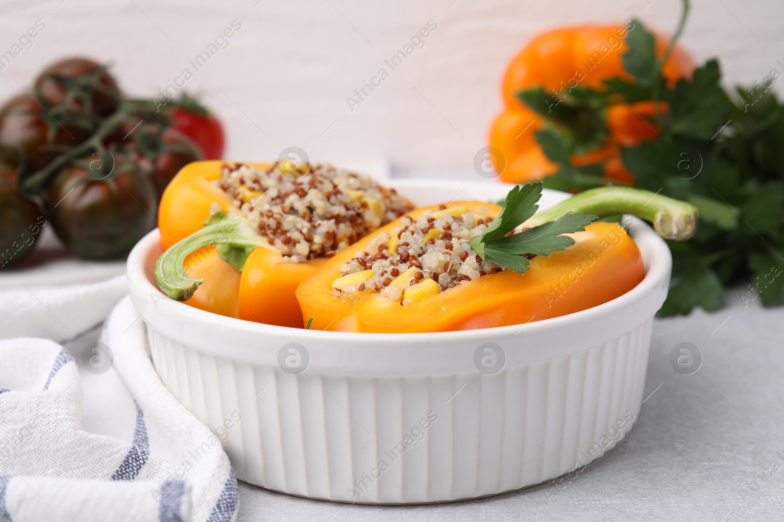 Photo of Quinoa stuffed bell pepper and parsley in bowl on light table, closeup