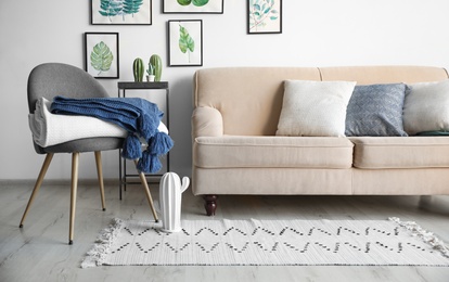 Stylish living room interior with comfortable sofa, chair and plaids