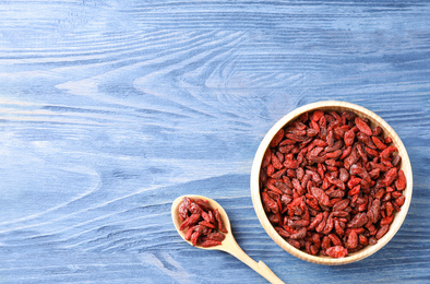 Dry goji berries on blue wooden table, flat lay. Space for text