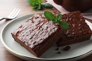 Delicious chocolate brownies with fresh mint served on wooden table, closeup