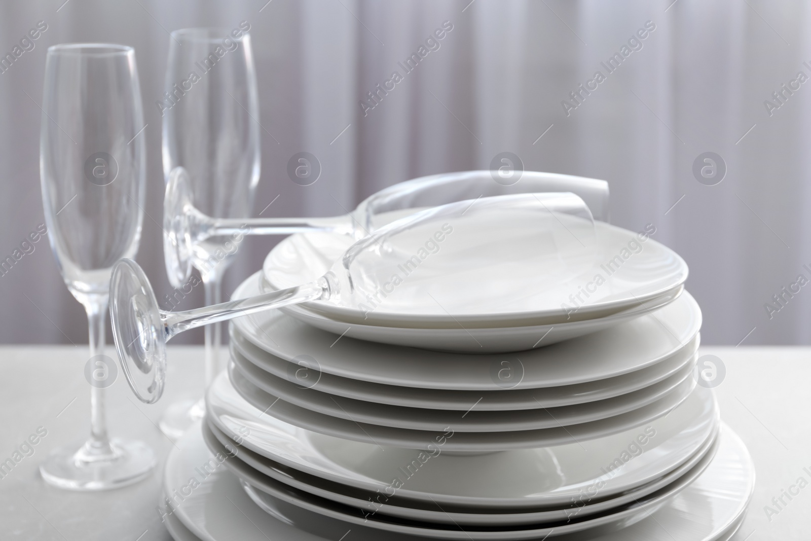Photo of Stacked plates and glasses on table, closeup