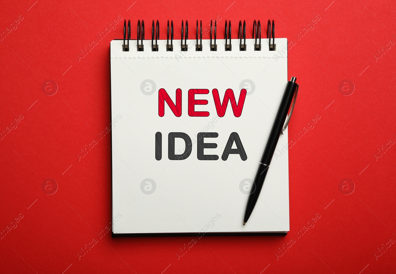 Image of Notebook with words NEW IDEA and pen on red background, top view