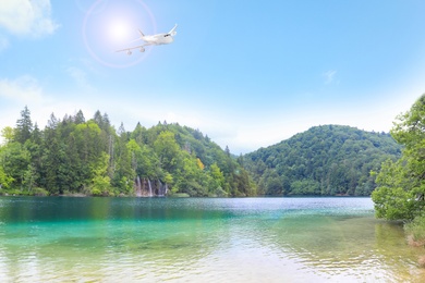 Image of Airplane flying in blue sky over river and mountains