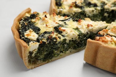 Delicious homemade spinach quiche on white table, closeup