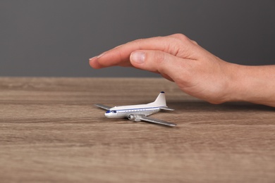Photo of Woman covering toy plane on table, closeup view with space for text. Travel insurance concept