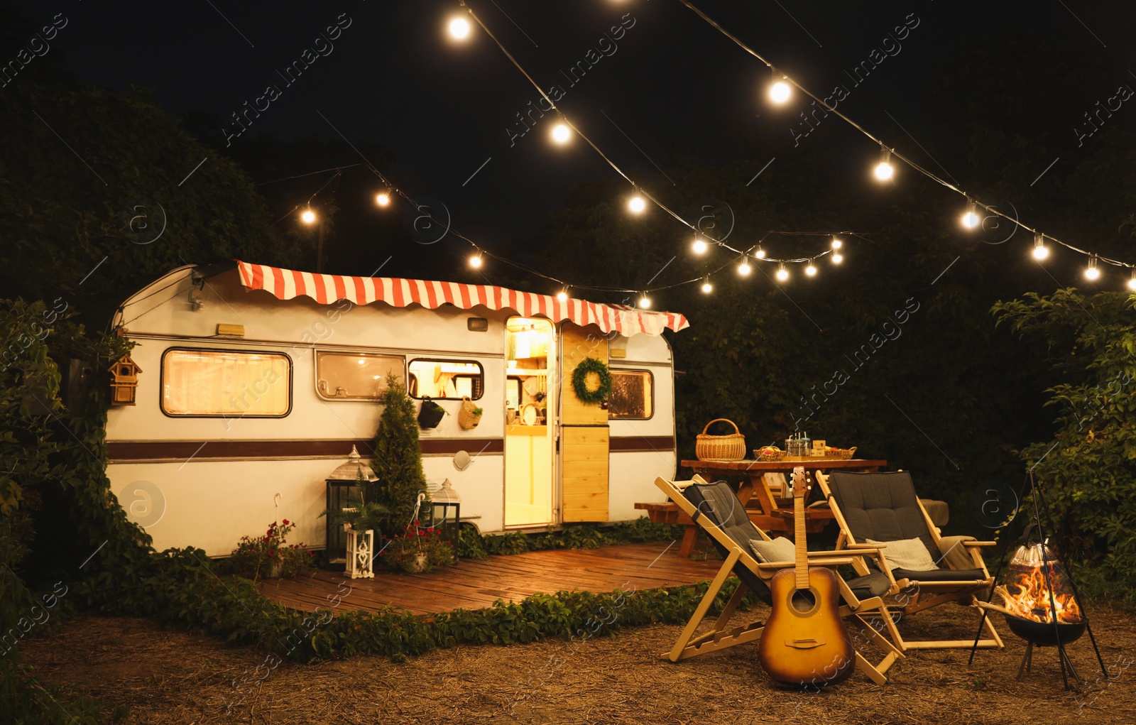 Image of Water heating on open fire near trailer at night. Camping season