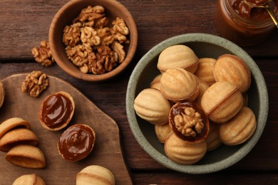 Delicious nut shaped cookies with boiled condensed milk on wooden table, flat lay