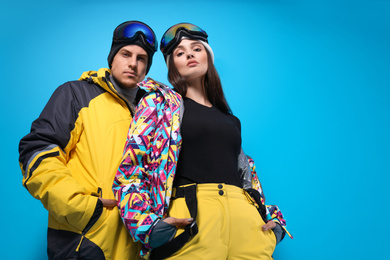 Photo of Couple wearing stylish winter sport clothes on light blue background, low angle view