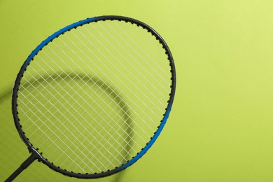 Photo of Badminton racket on light green background, closeup. Space for text