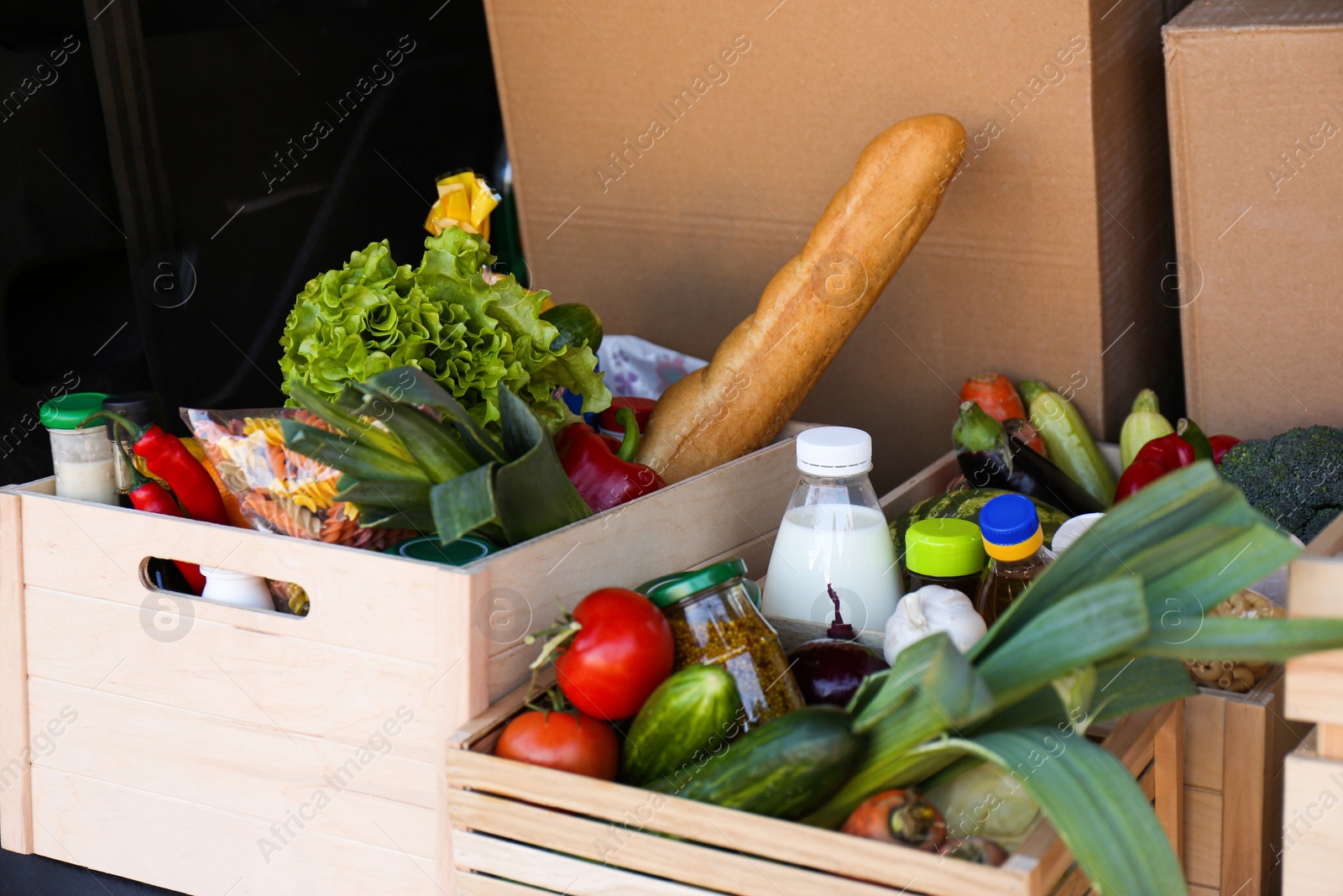 Photo of Wooden crates with fresh products in car trunk. Food delivery service