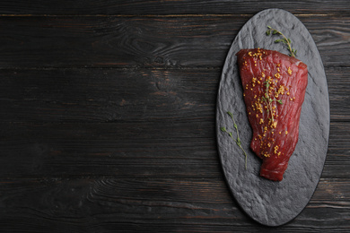 Photo of Fresh raw beef cut with thyme and mustard on wooden table, top view. Space for text