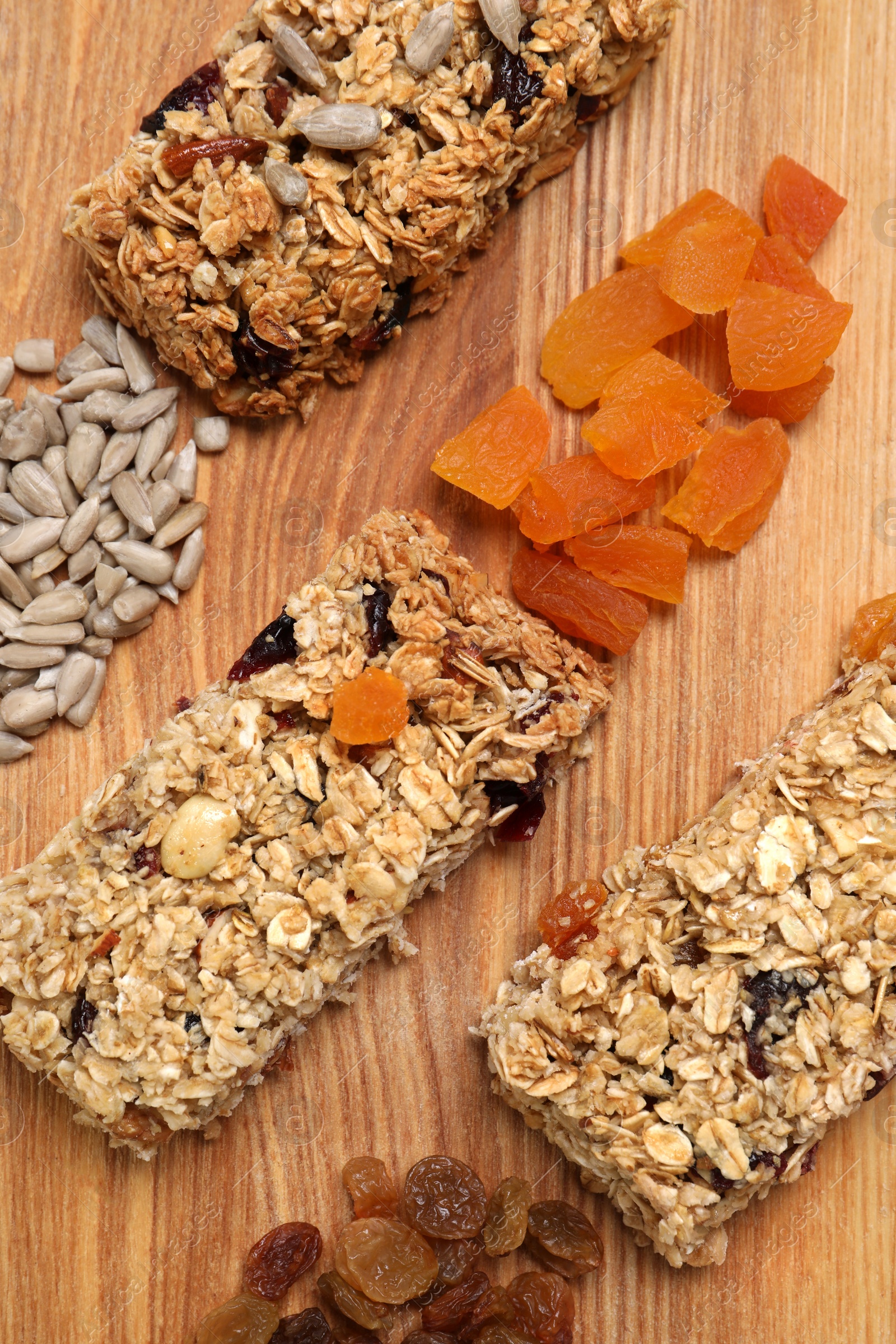 Photo of Different tasty granola bars and ingredients on wooden table, flat lay