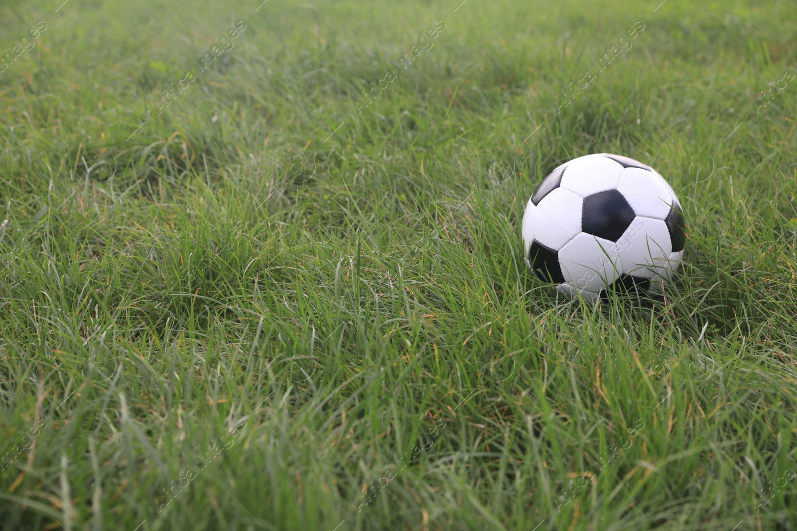 Photo of Dirty soccer ball on green grass outdoors, space for text