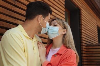 Photo of Couple in medical masks trying to kiss outdoors