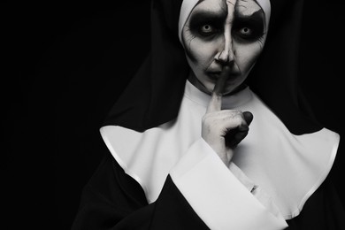 Photo of Portrait of scary devilish nun on black background, space for text. Halloween party look