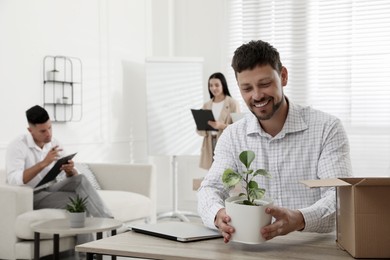 Photo of New coworker with plant at workplace in office