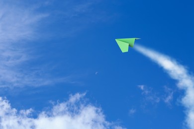 Image of Green paper plane flying in blue sky with clouds