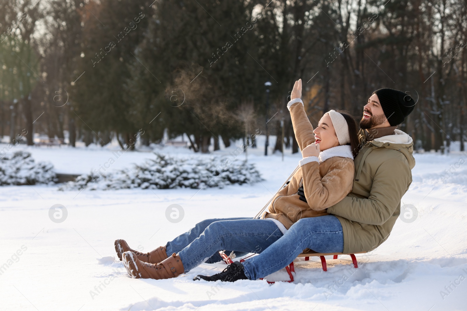 Photo of Happy young couple sledding outdoors on winter day