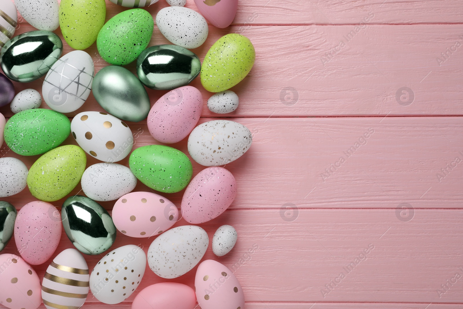 Photo of Many beautifully decorated Easter eggs on pink wooden table, flat lay. Space for text