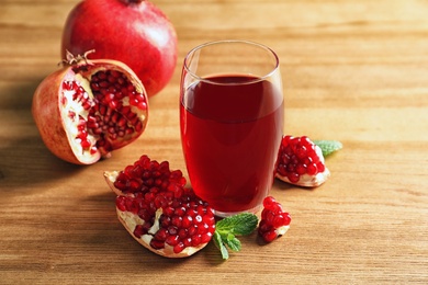 Photo of Glass of pomegranate juice and fresh fruits on wooden background