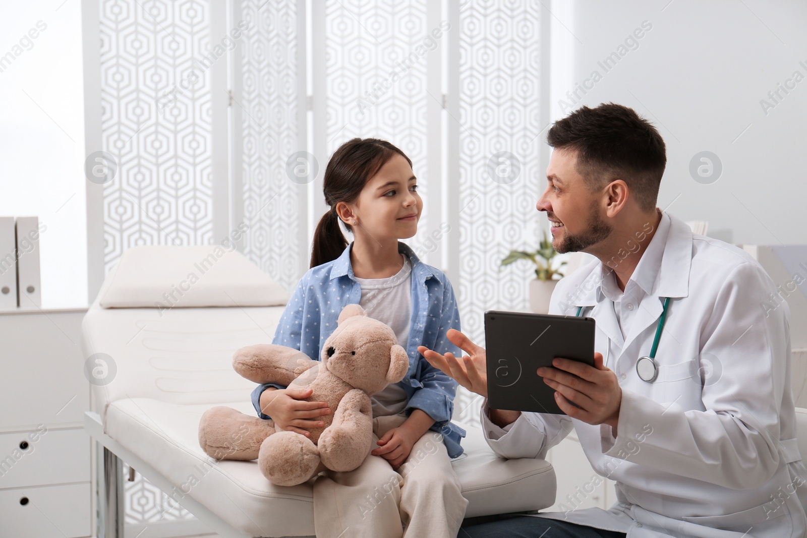 Photo of Pediatrician explaining physical examination result to little girl in hospital