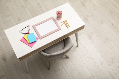 Empty frame and stationery on white table indoors, above view