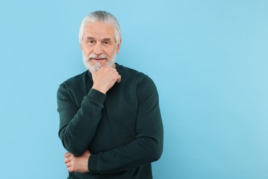 Photo of Portrait of handsome senior man on light blue background. Space for text