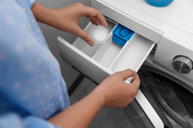 Photo of Woman pouring laundry detergent into drawer of washing machine indoors, above view