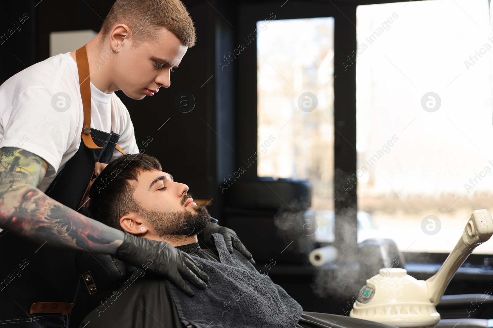 Photo of Professional hairdresser working with bearded client in barbershop