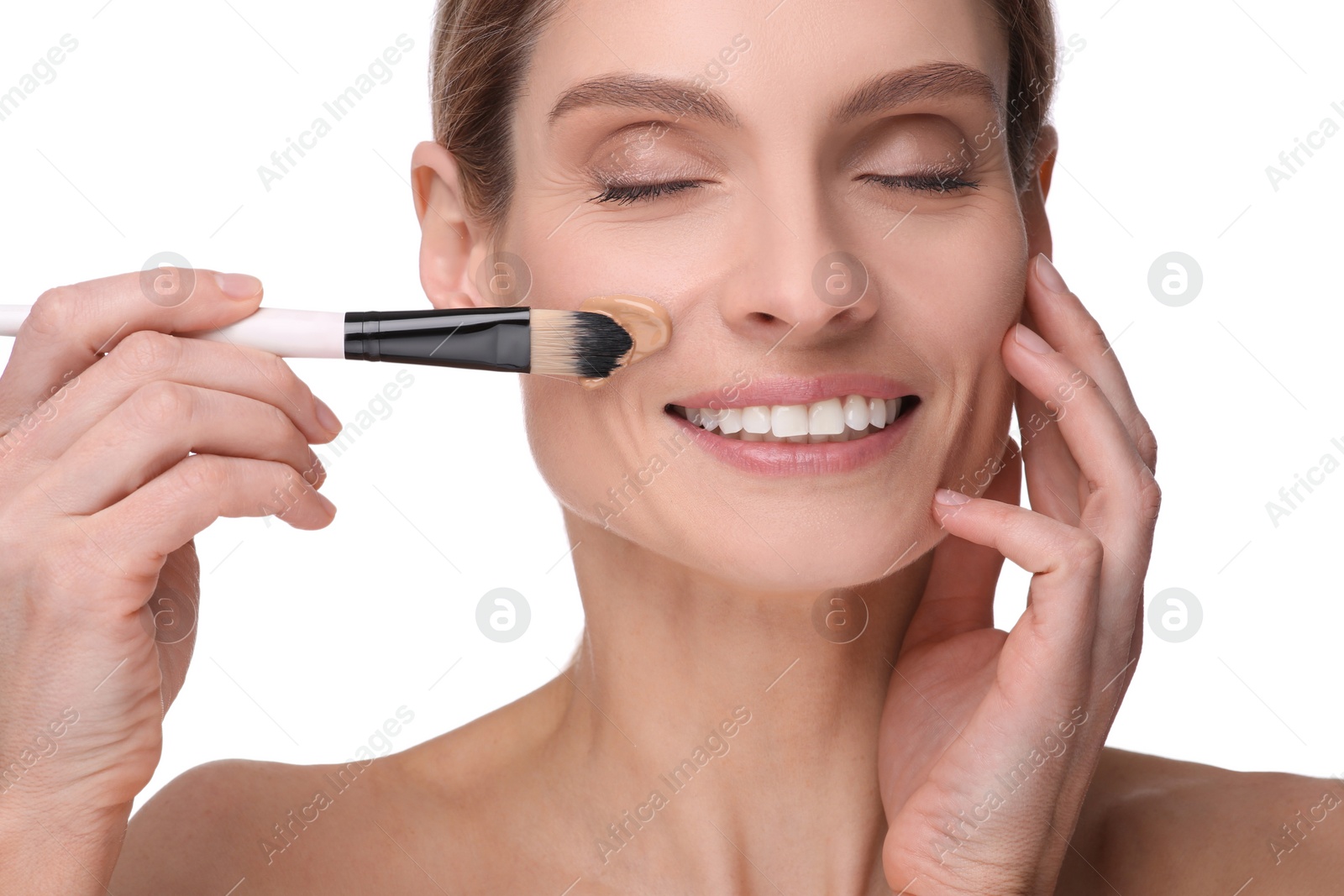 Photo of Woman applying foundation on face with brush against white background