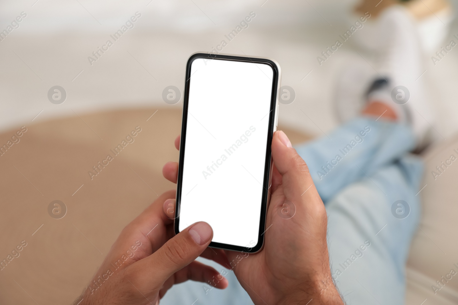 Photo of Man holding mobile phone with empty screen indoors, closeup