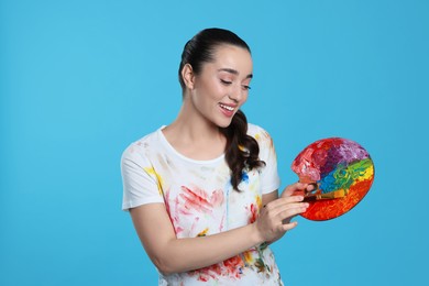 Photo of Woman with painting tools on light blue background. Young artist