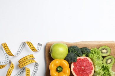 Photo of Fruits, vegetables and measuring tape on white background, top view. Visiting nutritionist