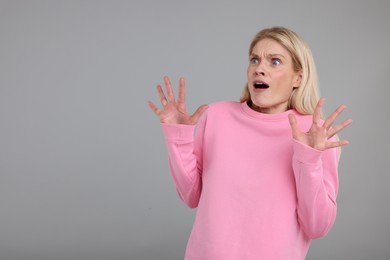 Portrait of surprised woman on grey background, space for text