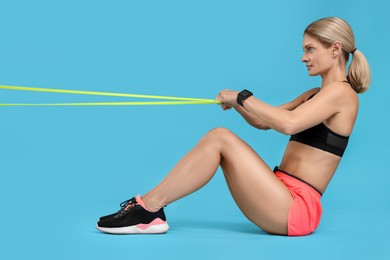 Photo of Woman exercising with elastic resistance band on light blue background