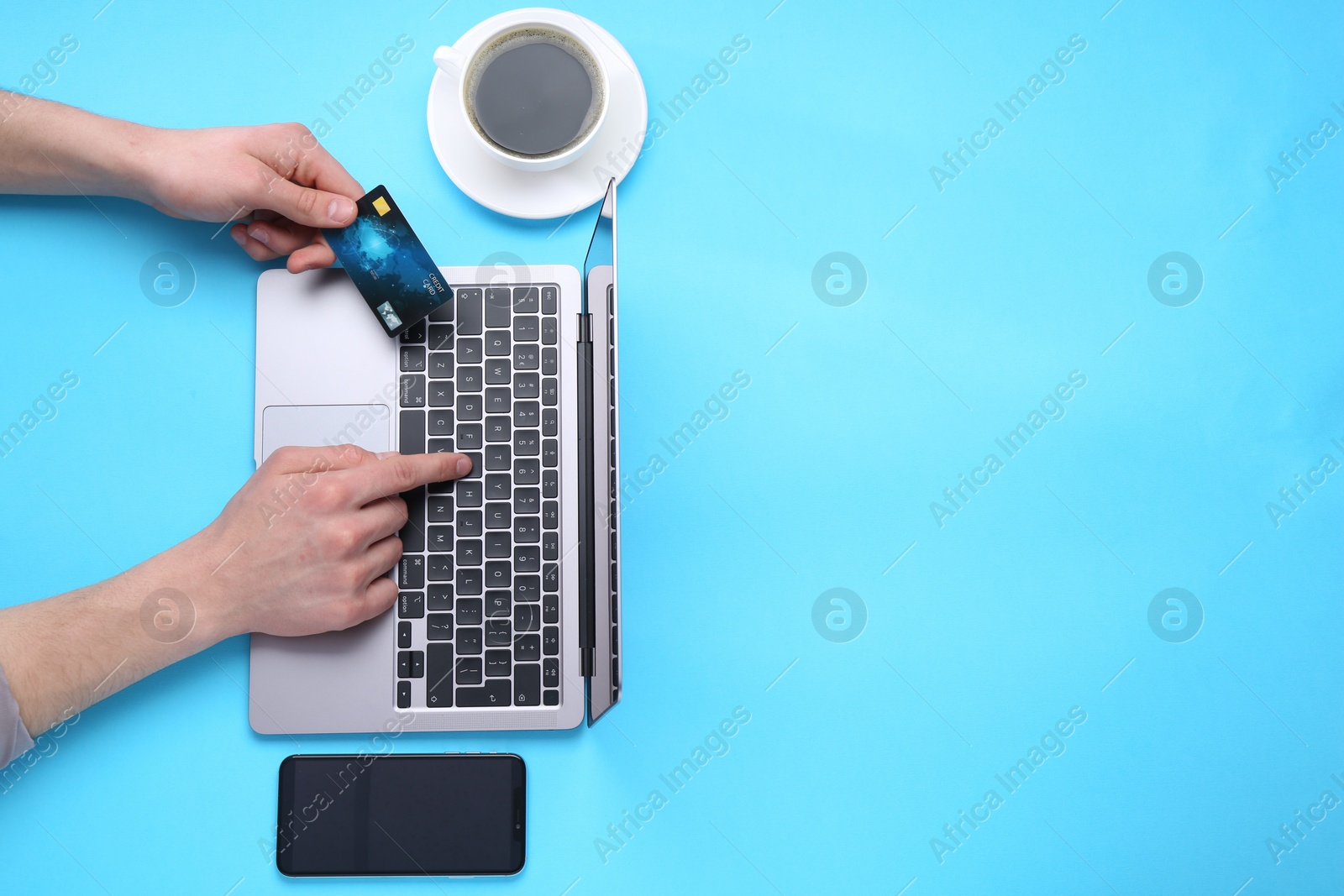 Photo of Online payment. Man with laptop, credit card, smartphone and coffee on light blue background, top view. Space for text