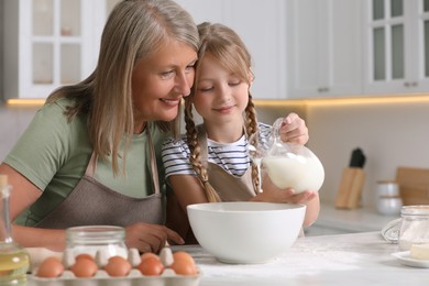 Photo of Happy grandmother with her granddaughter cooking together in kitchen