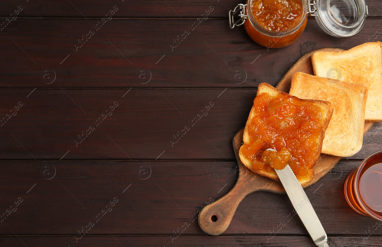 Photo of Delicious toasts with jam served with tea on wooden table, flat lay. Space for text