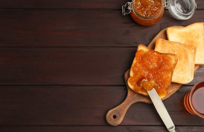 Photo of Delicious toasts with jam served with tea on wooden table, flat lay. Space for text