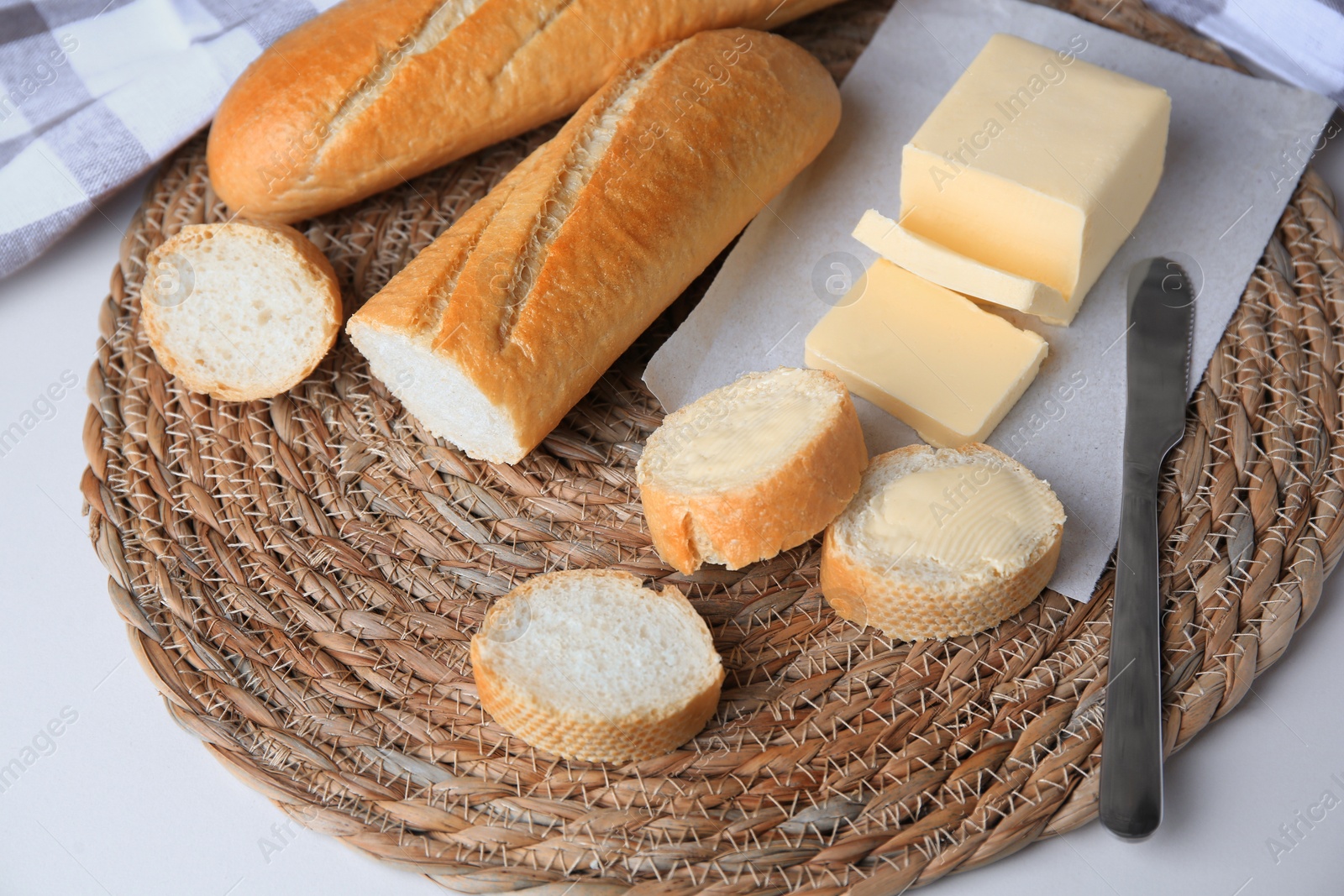 Photo of Tasty cut baguette with fresh butter on white table