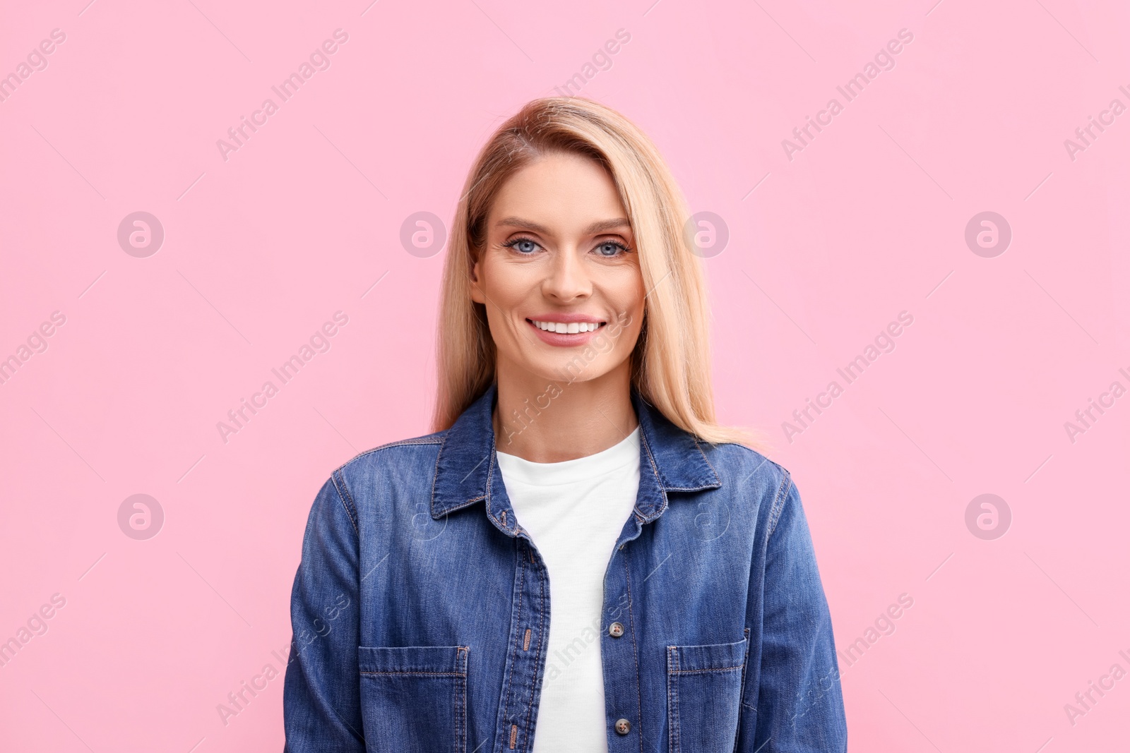 Photo of Portrait of smiling middle aged woman with blonde hair on pink background