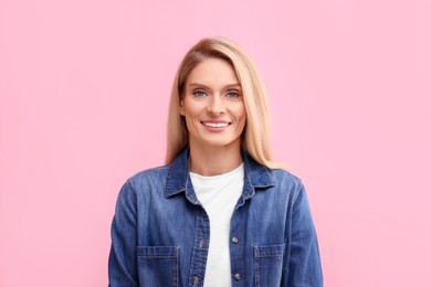 Photo of Portrait of smiling middle aged woman with blonde hair on pink background