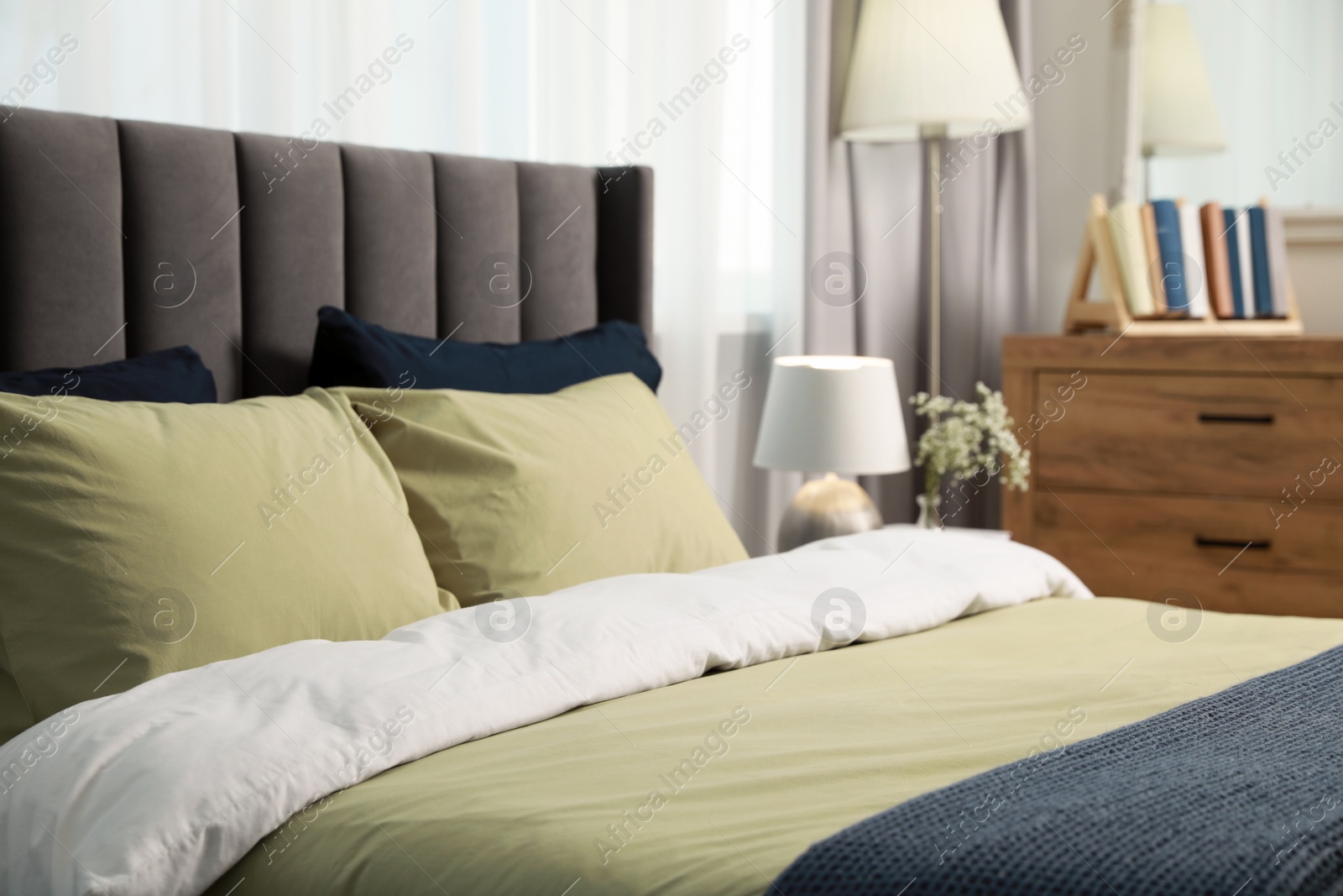 Photo of Comfortable bed with cushions and bedding in room. Stylish interior