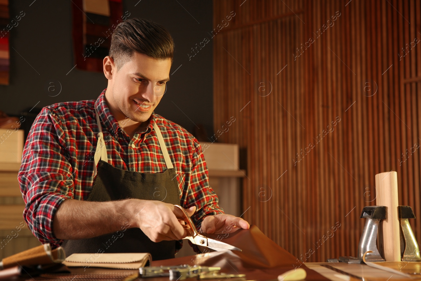 Photo of Man cutting leather with scissors in workshop